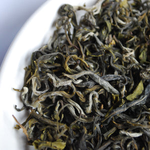 Closeup of loose dried tea leaves in a white bowl